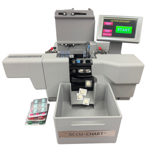 A gray Cuttin Station pill cutter with a touchscreen showing "Cuttin Station" and a green START button slices pills into smaller pieces that drop into a bin, while uncut pills are seen to the side.