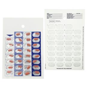 A blister pack of red and white capsules next to a white card with labeled spaces for medication tracking; both are laid out against a white background.
