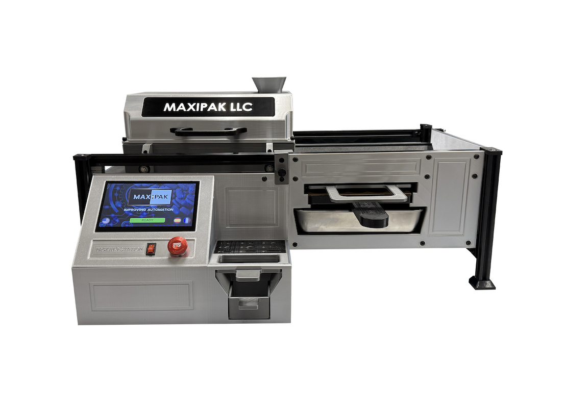 A compact, silver industrial machine labeled MAXIPAK LLC featuring a touchscreen interface, control buttons, and a rectangular processing area, set against a white background.