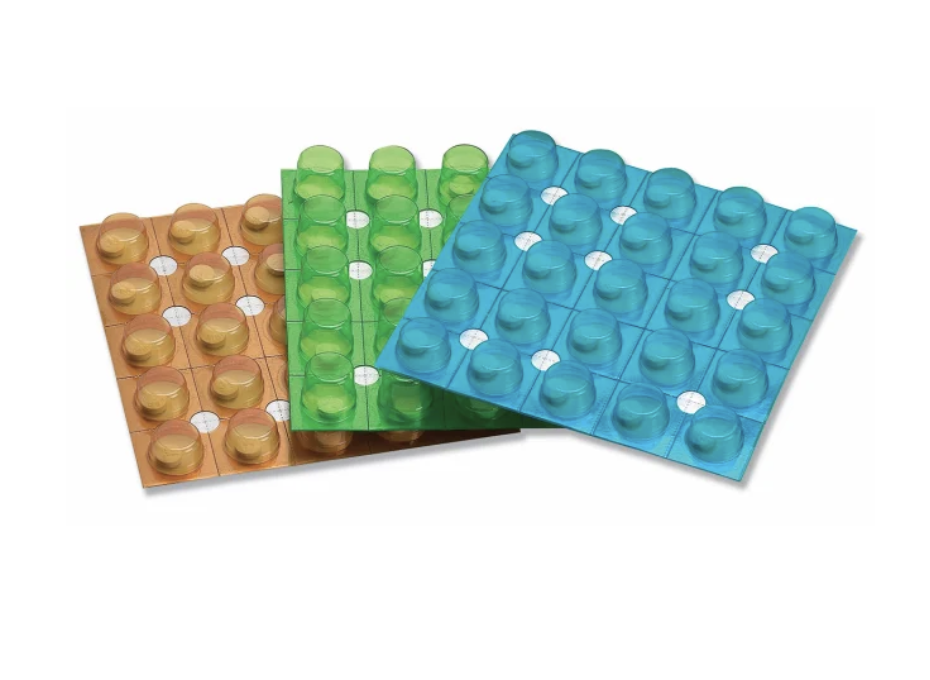 Three Unit Dose Blisters & Cards in orange, green, and blue, each with multiple round cavities in a grid pattern, are displayed overlapping on a white background.